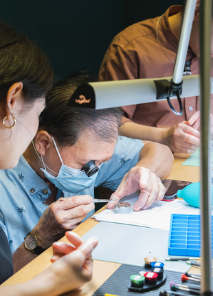 Watchmaking instructor guiding a participant through mechanical watch assembly at The Watch Academy workshop in Singapore.